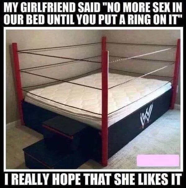 A bedroom mattress built into a WWE wrestling ring with ropes and corner posts, with text about taking a girlfriend's request to put a ring on the bed literally.